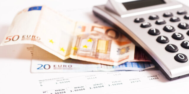 bancnote alaturi de un calculator de mana